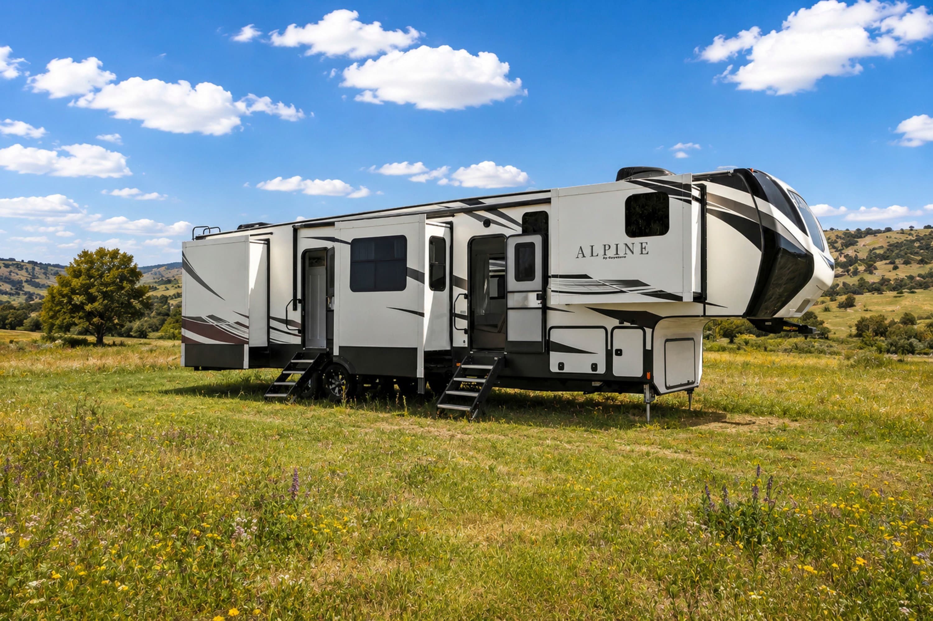 Side exterior view of large fifth-wheel RV with slide-outs parked in a grassy field.