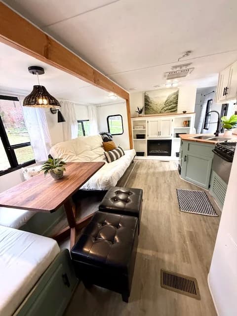 RV living area with futon sofa, dinette, fireplace, and mint green kitchen cabinets.