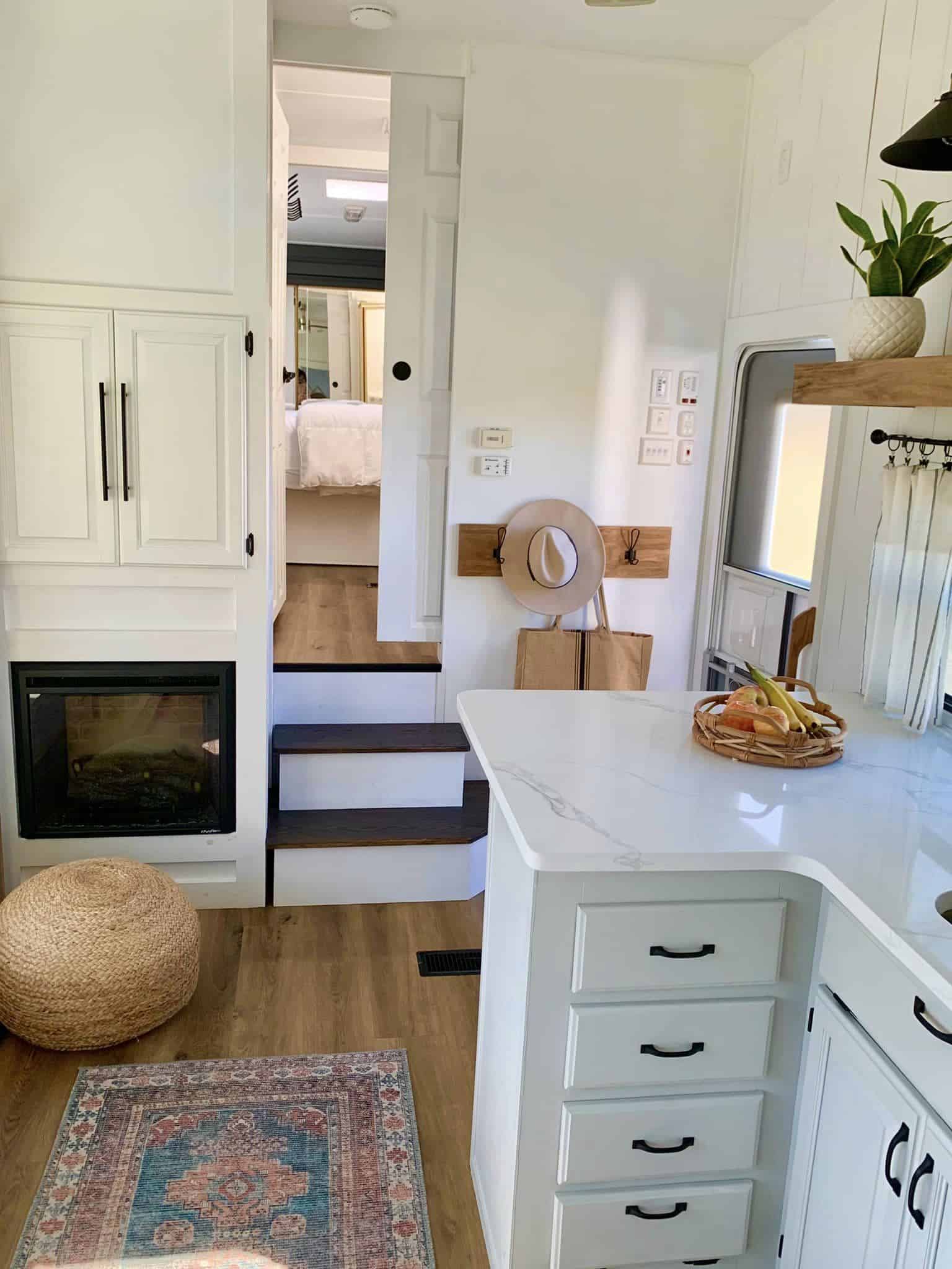 RV kitchen island and fireplace with steps leading up to the bedroom.