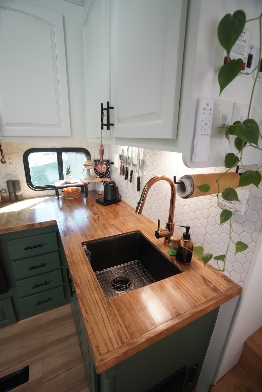 Close view of RV kitchen sink with wood countertop and hex tile backsplash.
