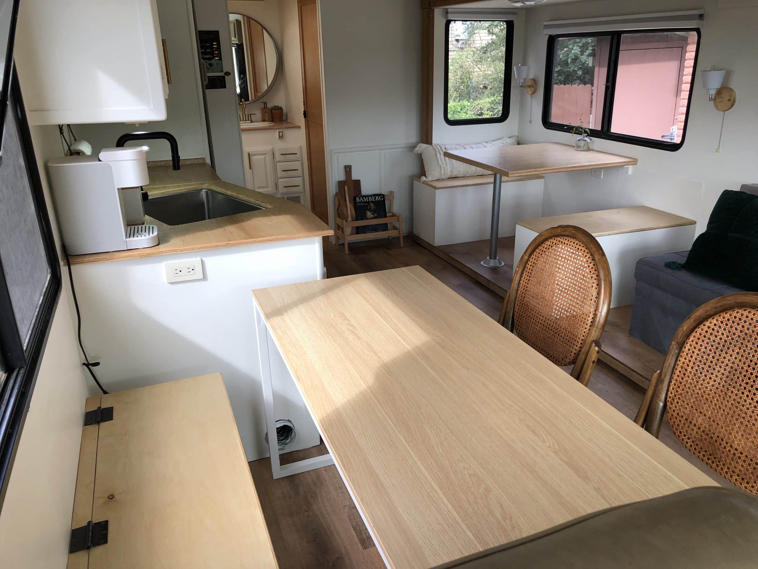 RV interior showing built-in desk, storage bench, and rear dinette seating.